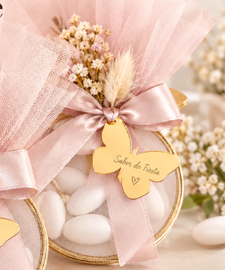 Bolsitas de tul con peladillas y espiga seca, atadas con lazo rosa.