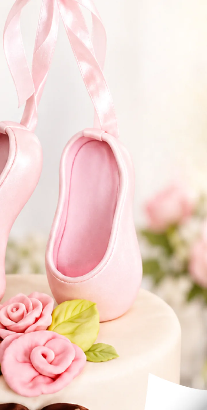 Tarta decorada con zapatillas de ballet de azúcar y rosas modeladas.
